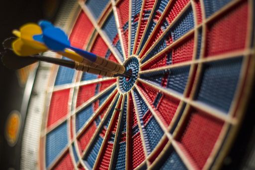 A closeup shot of a dartboard with three darts in the center