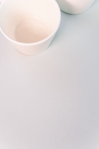 A vertical shot of empty white coffee cups placed on a white surface