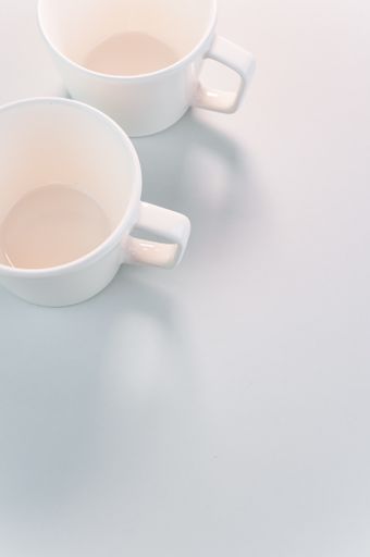 A vertical shot of empty white coffee cups placed on a white surface