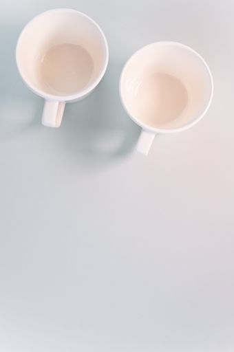 A vertical shot of empty white coffee cups placed on a white surface