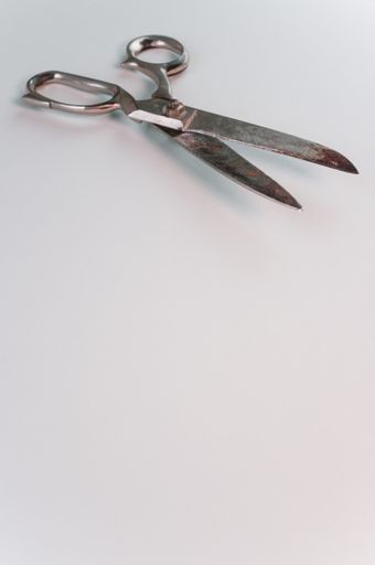A vertical shot of old grunge carbon steel scissors on a white surface