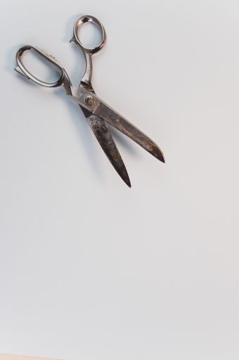 A vertical shot of old grunge carbon steel scissors on a white surface