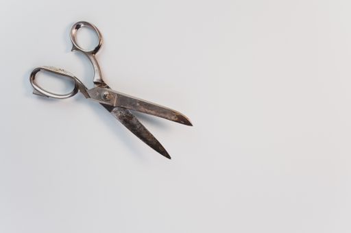 A top view of old grunge carbon steel scissors on a white surface