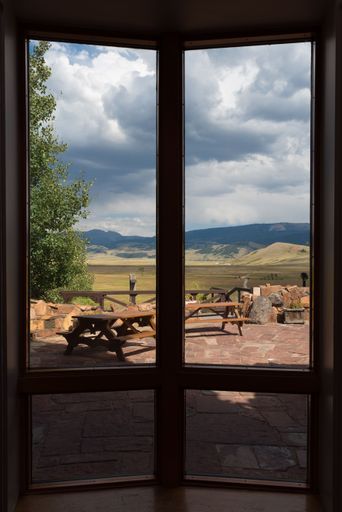 A beautiful landscape with wooden tables on a balcony in Jackson, Wyoming, seen from glass panel doors
