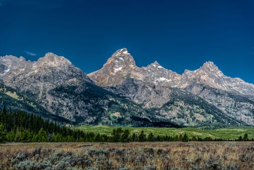 The Grand Teton National Park landscape with greenery and high hills against the blue sky in Wyoming