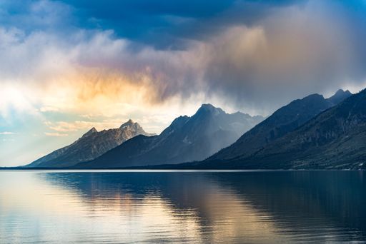 The Grand Teton National Park hills reflected in the water below at a sunset in Wyoming, United States