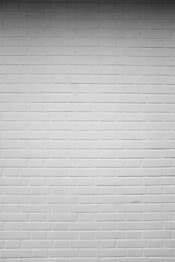 A cool background of a white painted stone wall under lights in a room