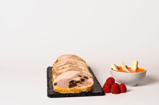 close-up of a chicken stuffed with raspberry and goat cheese with a bowl of raspberry sauce isolated on white background