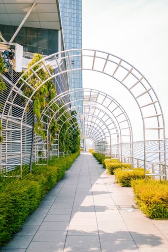 A vertical shot of a metal arch over a sidewalk near a building