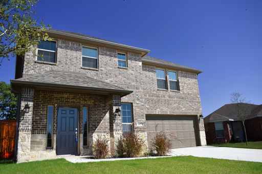 A gray building  with a garage and a grassy yard under the clear blue sky