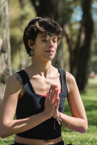 A vertical shot of a young Caucasian female doing yoga practice in the park