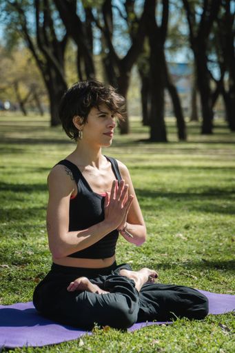 A vertical shot of a young Caucasian female doing yoga practice in the park