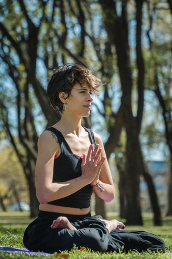 A vertical shot of a young Caucasian female doing yoga practice in the park