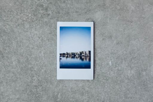 A Polaroid pictures of the ocean and the cliff on a grey surface