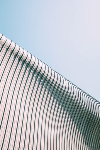 A low angle shot of a grey and white building roof with interesting textures under the blue sky