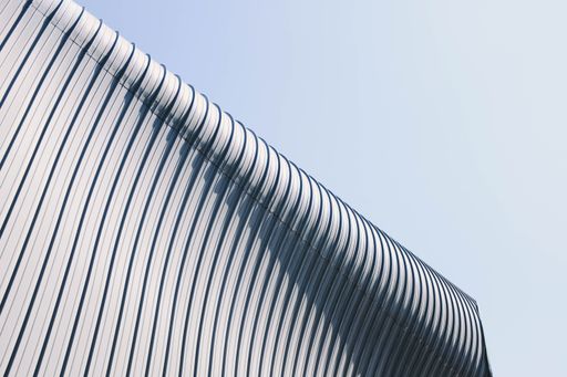 A low angle shot of a grey and white building roof with interesting textures under the blue sky