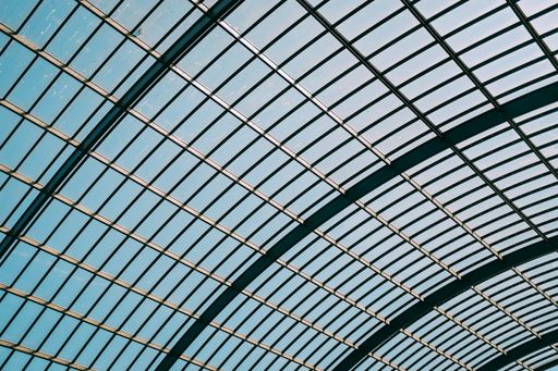 A low angle shot of a glass roof of a modern building under the blue sky