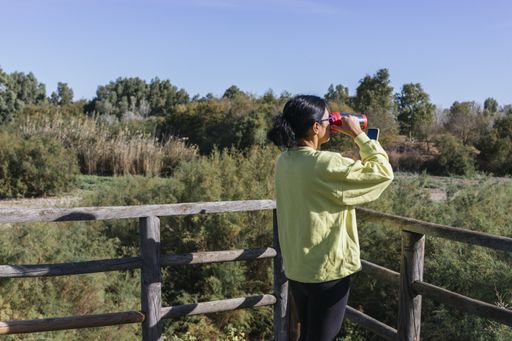 A young woman drinking water after jogging