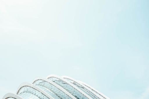 A low angle shot of a glass building with the bright blue sky in the background