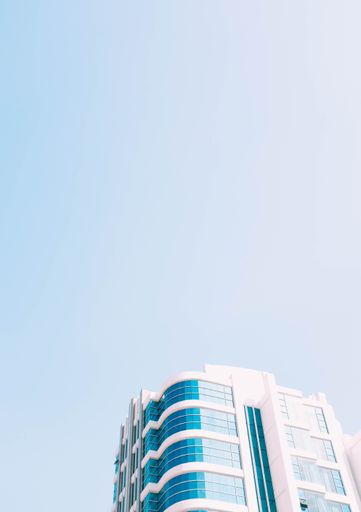 A vertical low angle shot of a glass building under the blue sky captured in Singapore