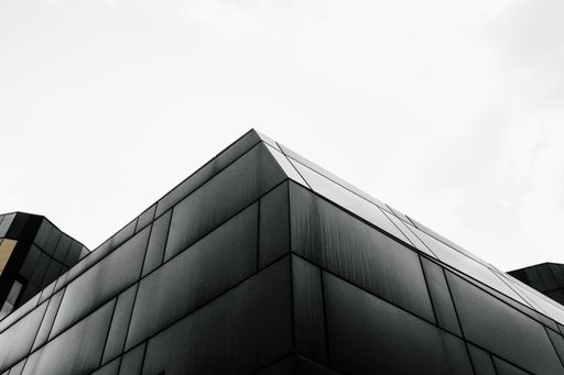 A low angle grey scale shot of a geometrical building under the bright sky