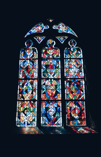 A vertical shot of a beautiful colorful window in a dark room