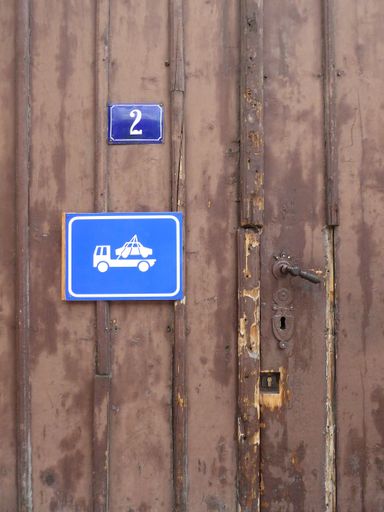 a vertical shot of a door with key lock and doorknob with a number and tow truck sign