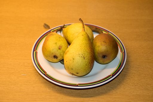 A closeup shot of the ripe and delicious pears on the plate on the wooden surface