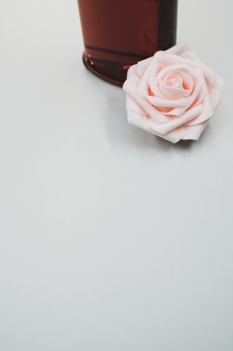 A bottle of nice perfume with a beautiful rose flower on a white background