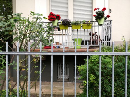 A view of a balcony with green bushes near the fence