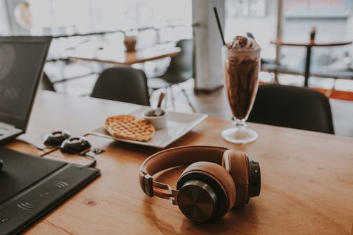 A closeup shot of technological objects on a cafe table next to dessert