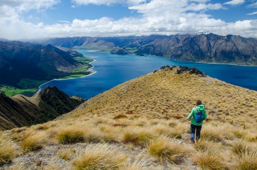 A closeup shot of a female walking at the Isthmus Peak and a lake in New Zealand