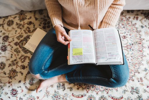 Woman reading the Bible on floor with rug.