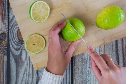 A top view of woman hands cutting lemons on chopping board