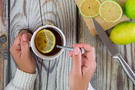 A top view of woman hands with a cup of tea on a wooden table