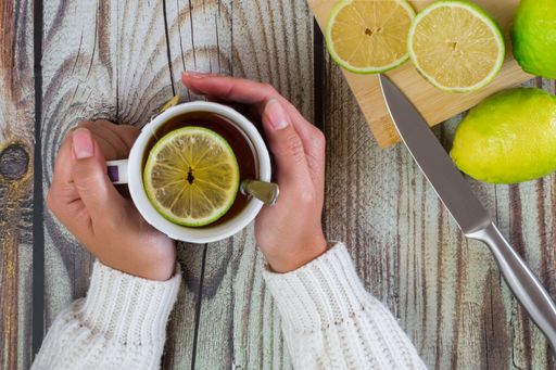 A top view of woman hands with a cup of tea on a wooden table