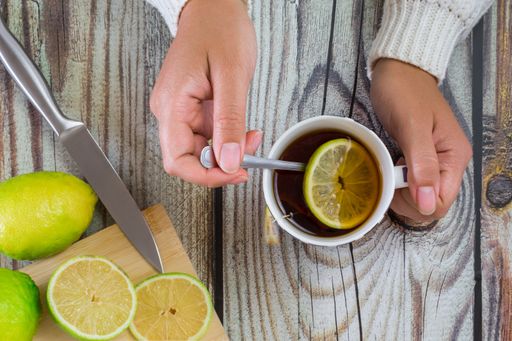 A top view of woman hands with a cup of tea on a wooden table