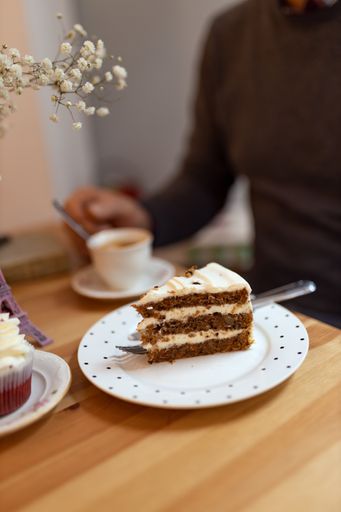A piece of cake accompanied by a cup of coffee and cupcake