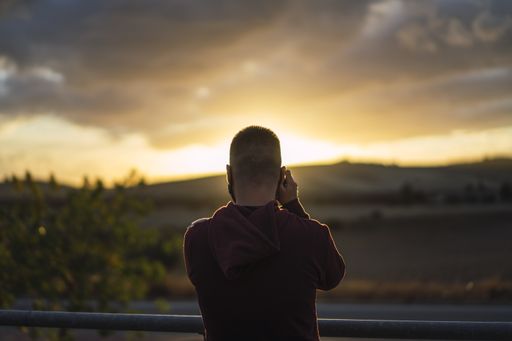 A selective focus shot of a young man taking a photo of a landscape