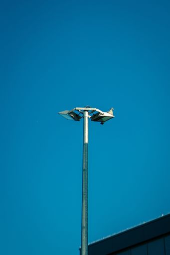 A low angle shot of street lighting under a blue sky