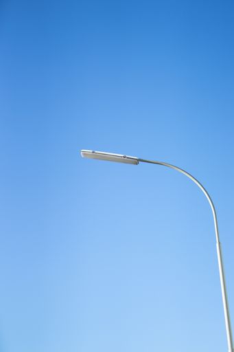 A low angle shot of street lighting under a blue sky