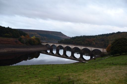 The arch-like bridge over Ladybower Reservoir with lush trees in distance