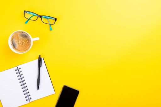 The flat lay of the office working tools on the yellow surface - space for text