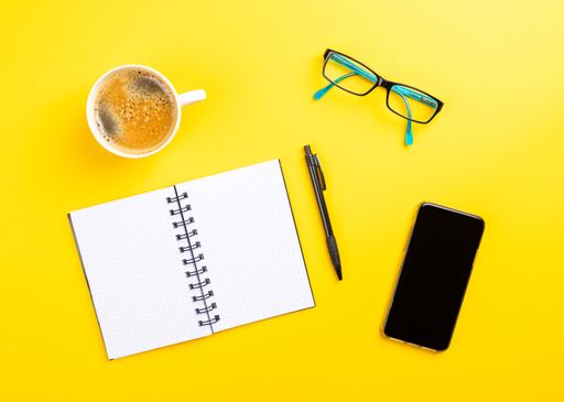 The flat lay of the office working tools on the yellow surface - space for text