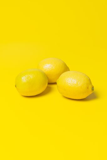 A vertical shot of lemons on yellow background with an empty space for a text