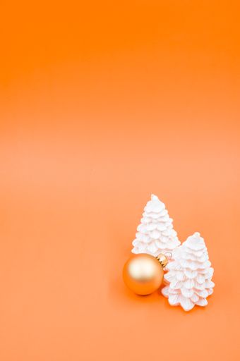 A vertical shot of Christmas ornaments on an orange surface