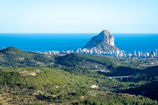 A scenic view of the Ifach rock and the coastal city of Calpe from afar