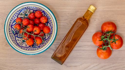A high angle shot of different tomatoes near an oil bottle
