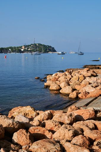 A closeup of big cobblestones on the beach in Mallorca, seascape with sailing boats in the background