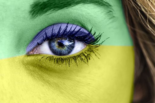 A closeup shot of a female's eye with the colors of the Brazilian flag